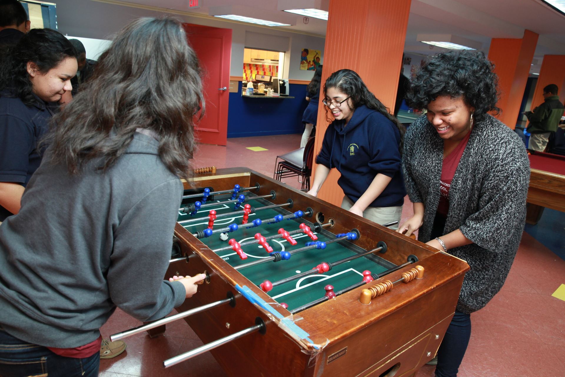 A group of young people playing foosball in a rec center.