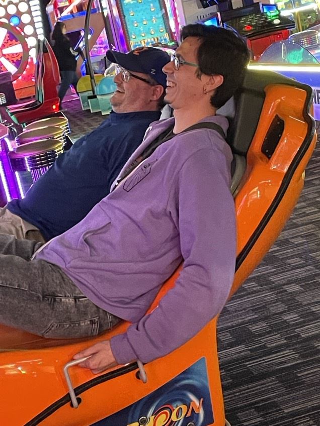 Two people smiling sitting in chairs at an arcade